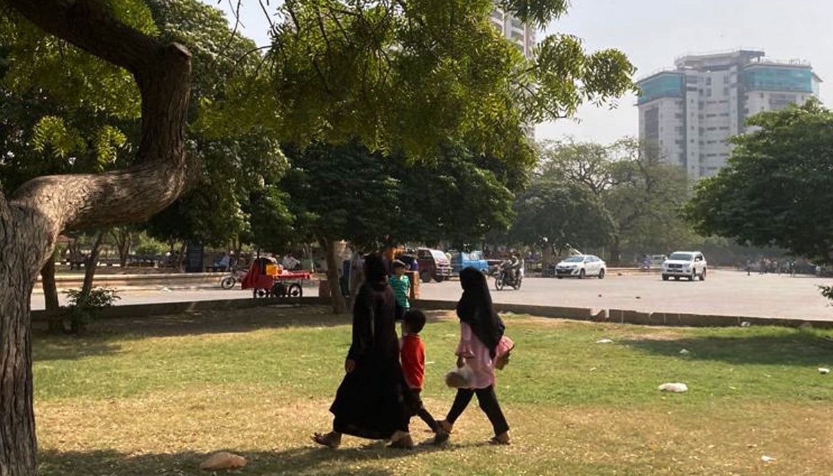 A woman walks with her young daughter and son as she approaches the Frere Hall gardens. — Photo by author