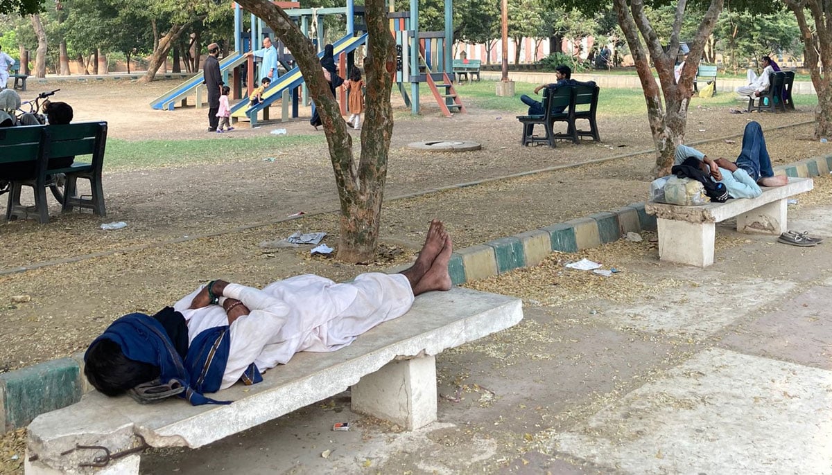 Men are seen lying on the benches to rest near the Frere Hall gardens. — Photo by author