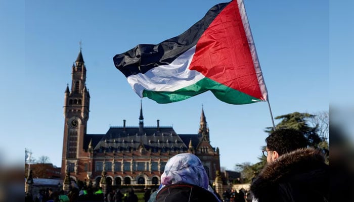 Protesters hold a Palestinian flag as they gather outside the International Court of Justice (ICJ) as judges rule on emergency measures against Israel following accusations by South Africa that the Israeli military operation in Gaza is a state-led genocide, in The Hague, Netherlands, January 26, 2024. — Reuters