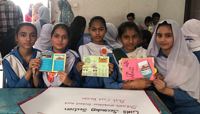 A group of female students are photographed here with the postcards they created in the competition. — Photo by author