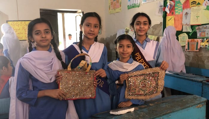 Students pose with their bag created using a flour bag and other waste materials. — Photo by author