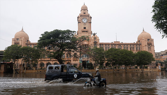 Vehicles drive through a flooded road in front of the colonial-era building of the Karachi Municipal Corporation (KMC), after a thunderstorm in Karachi, February 4, 2024. — Reuters