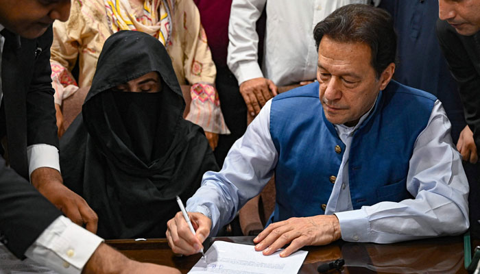 Pakistans former Prime Minister, Imran Khan (C) along with his wife Bushra Bibi (C, left) signs surety bonds for bail in various cases, at a registrars office in the Lahore High Court, in Lahore on July 17, 2023. — AFP