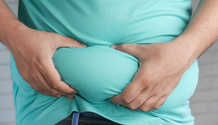 A representational image showing a man holding his belly. — Unsplash