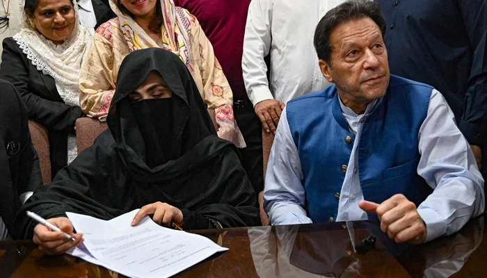 Former prime minister Imran Khan along with his wife Bushra Bibi signs surety bonds for bail in various cases, at the registrars office in the Lahore High Court on July 17, 2023. — AFP