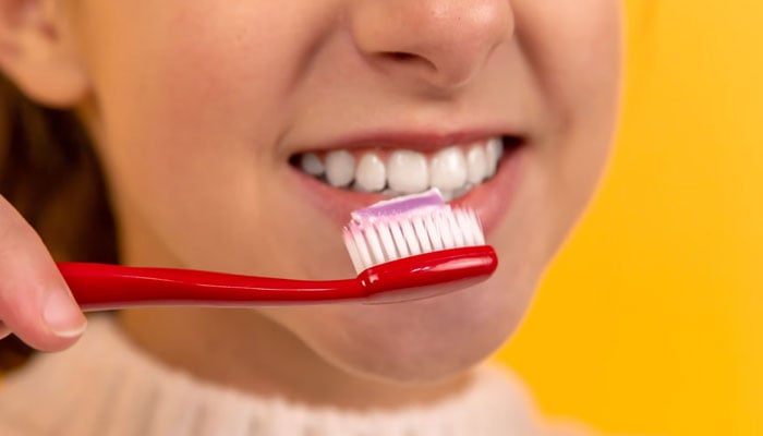 A girl brushes her teeth with toothpaste and a toothbrush. — Unsplash