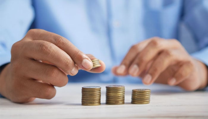 A man stacks coins on a table. — Unsplash