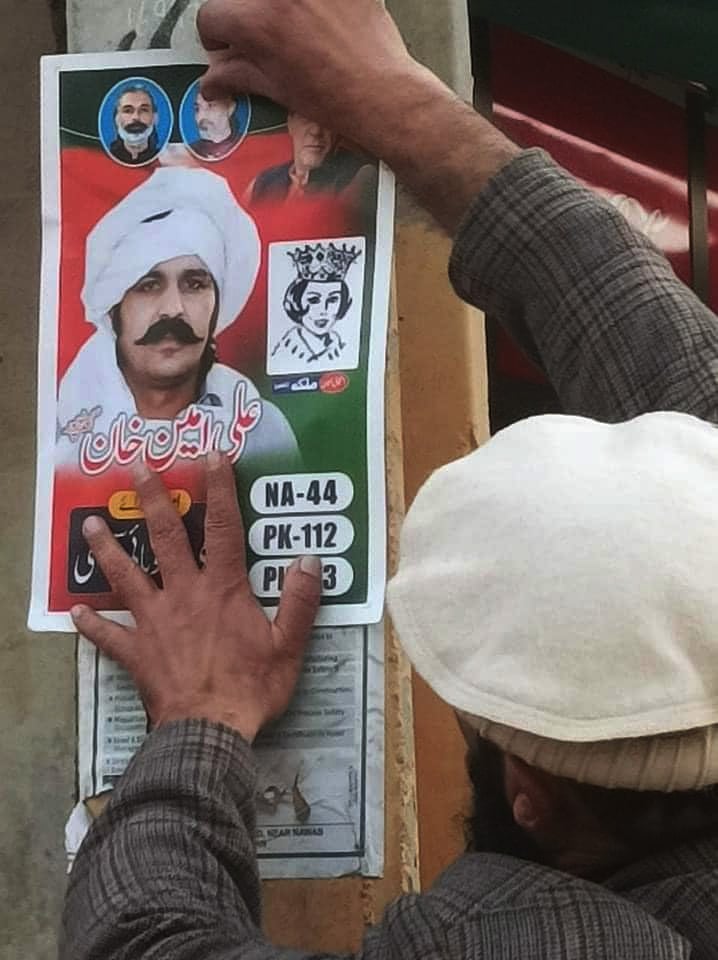 A PTI worker installing Ali Amin Gandapur’s poster on the wall during electioneering for the February 8 general elections in this undated photo. — Facebook/AliAminKhanGandapurPti