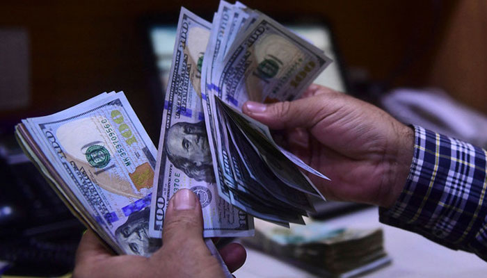 A dealer counts US dollars at a money exchange market in Karachi, Pakistan on March 2, 2023. — AFP