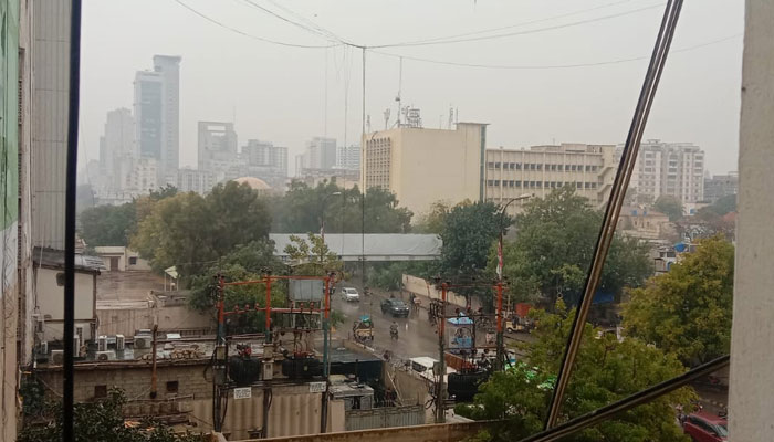 Commuters make their way to a road amid rain showers in Karachi on March 1, 2024. — Geo.tv