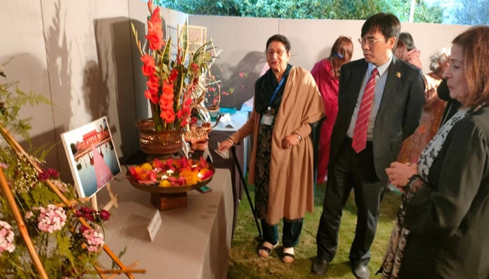 Participants and embassy officials examine various displays during the floral exhibition. — Reporter/File