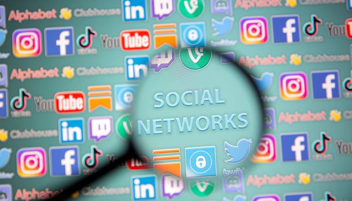 Social network words and social media logos are seen through magnifier displayed in this illustration taken, May 25, 2021. — Reuters