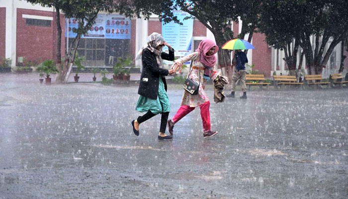 Students on the way to the University of Sargodha during the rain on March 2, 2024. — APP
