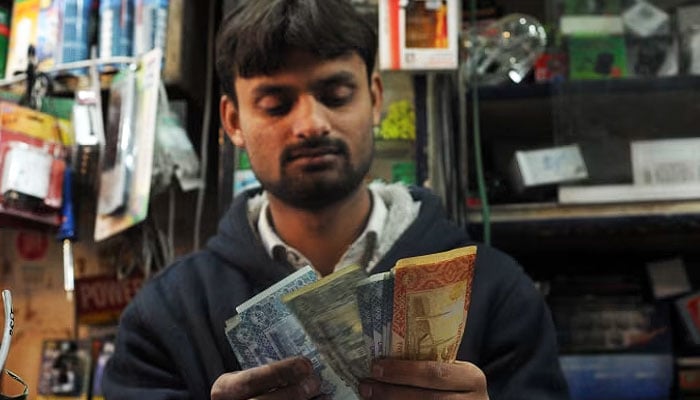 A Pakistani shopkeeper counts money at a store in Islamabad. — AFP/File