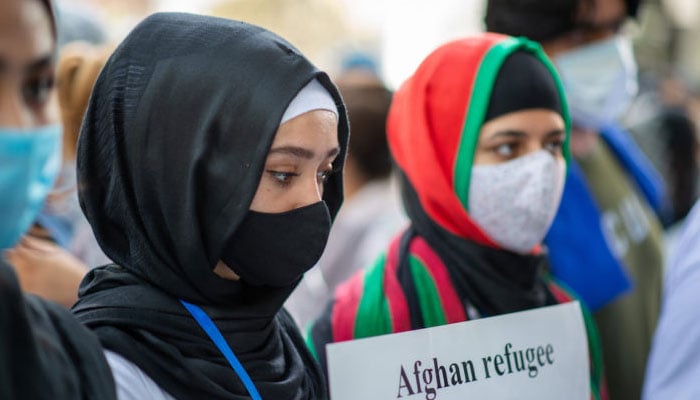 Afghan girls hold a placard during protests demanding refugee rights for Afghan women. — Europe Now/File