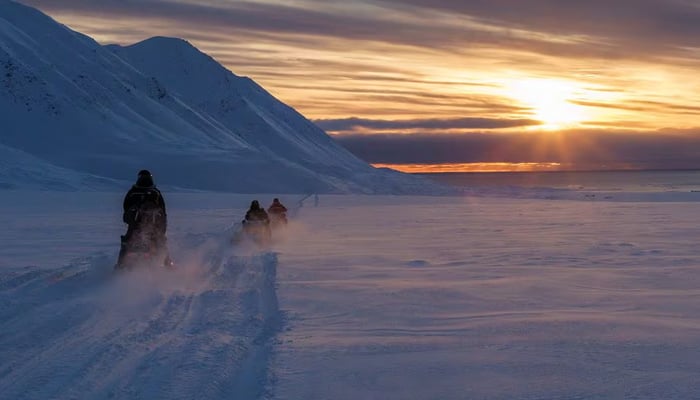 Scientists drive their snowmobiles cross the arctic towards Kongsfjord during sunset in a nordic country in this undated image. — Reuters