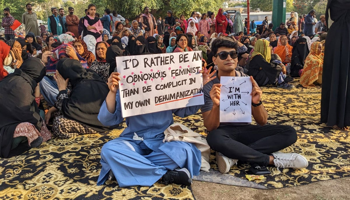A woman and a man holding placards in Aurat March at Frere Hall Karachi on March 8, 2024. — Author