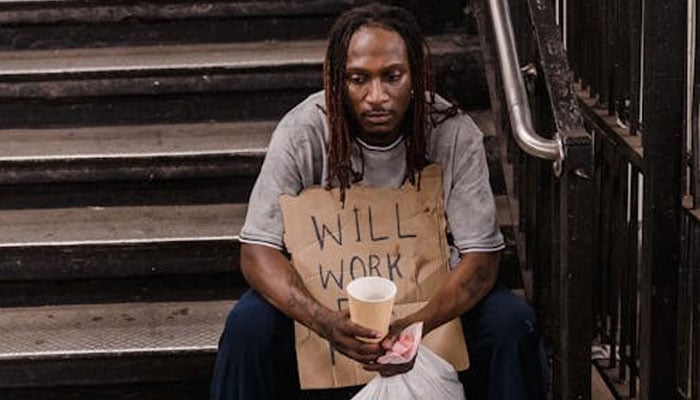 A representational picture of a homeless man sitting on the stairs. — Unsplash