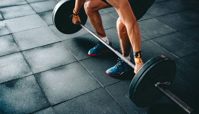 A man performs strength training through weightlifting. — Pexels