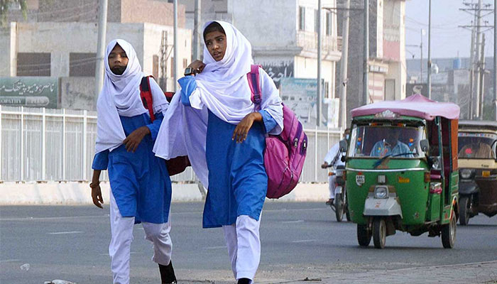 School girls walk down the road in this undated image. — APP