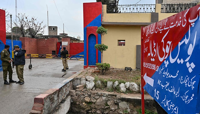 Police personnel stand guard near a signboard reading police check post Adiala at the entrance of Adiala jail after a hearing of jailed former prime minister Imran Khan in Rawalpindi on January 31, 2024. — AFP