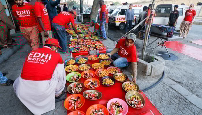 Volunteers of the Edhi Foundation, a non-profit social welfare programme, arrange food plates for the people to break their fast along a road in Karachi on April 3, 2023. — Reuters