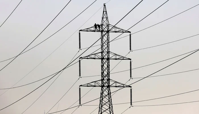 Technicians work to clean power transmission tower in Karachi, Pakistan, December 7, 2018. — Reuters