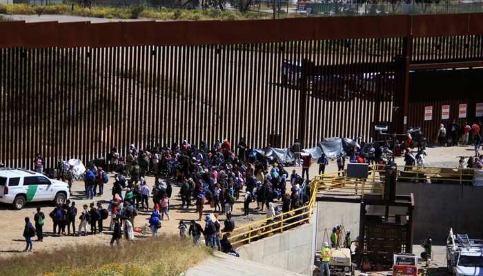 Migrants gather between the primary and secondary border fences in San Diego seen from Tijuana, Mexico on May 8, 2023. — Reuters