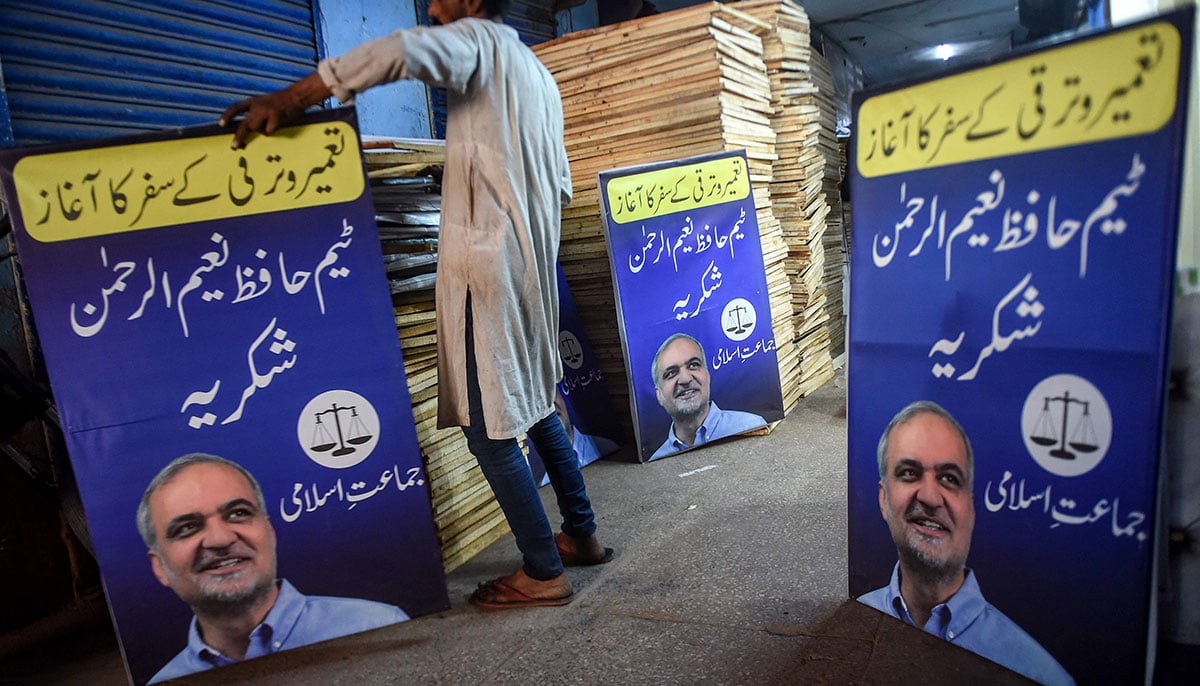 A worker arranges the posters of Jamaat-e-Islami (JI) party featuring their leader Hafiz Naeem ur Rehman, at a workshop in Karachi on January 12, 2024, ahead of the upcoming general elections. — AFP
