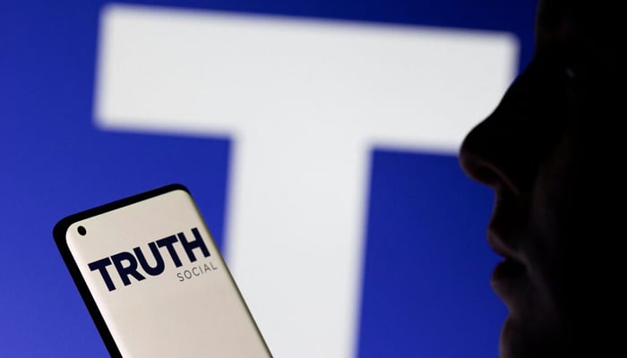 The Truth social network logo is seen displayed behind a woman holding a smartphone in this picture illustration taken February 21, 2022. — Reuters