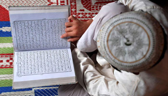 A Muslim boy reads the Quran at a madrasa or religious school on the first day of the holy month of Ramadan in the northern Indian city of Mathura August 23, 2009. — Reuters