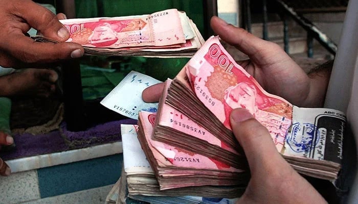 A person can be seen holding notes of Pakistani currency Rupee in the hands. — AFP/File
