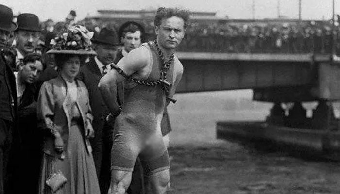 Harry Houdini in chains at the edge of a pier ready to dive in. — Metro via Corbis