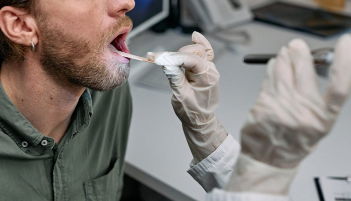 A representational image of a healthcare professional running a mouth test on a man. — Pexels