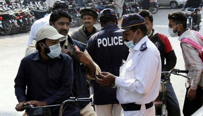 Traffic police staff issuing challan to people riding bikes without a helmet at Zainab Market in Karachi February 04, 2021. — PPI/File