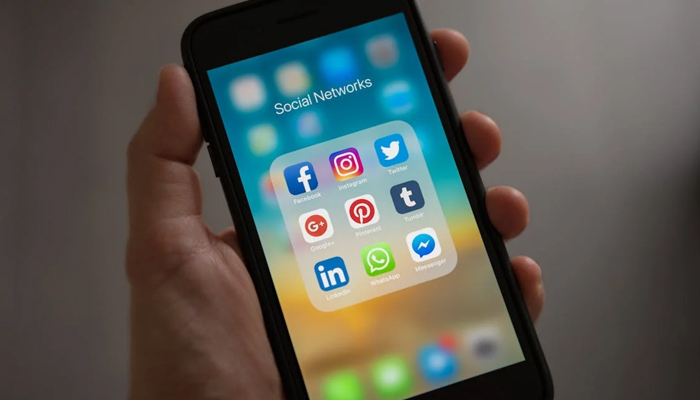 A representational image shows a mobile screen displaying social media platform icons. Florida bans under 13 children from using social media sites. — Pexels