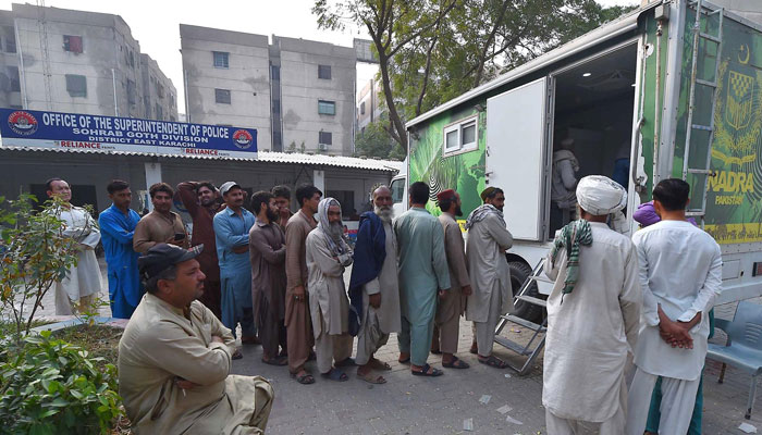 A large number of people wait outside SSP Office Sobhrab Goth, Karachi  for NADRA registration. —INP/File