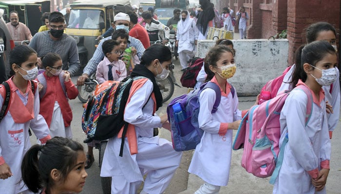 Students wearing facemasks arrive at a school in Lahore after Punjab government announcement smoggy conditions in the city on October 2, 2023. — Online
