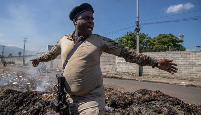 Former police officer Jimmy Barbeque Cherizier, leader of the G9 coalition, stands on a pile of rubbish as he talks about living conditions in the La Saline shanty area in Port-au-Prince, Haiti November 3, 2021. - Reuters