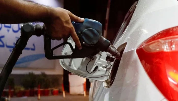 A worker holds a fuel nozzle to fills fuel in a car, after the government announced the increase of petrol and diesel prices, at petrol station in Karachi, Pakistan September 16, 2023. — Reuters
