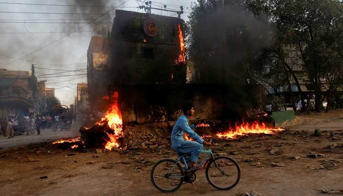 A boy rides past a paramilitary check post, that was set afire by the supporters of PTI Chairman Imran Khan, during a protest against his arrest, in Karachi, Pakistan May 9, 2023. — Reuters