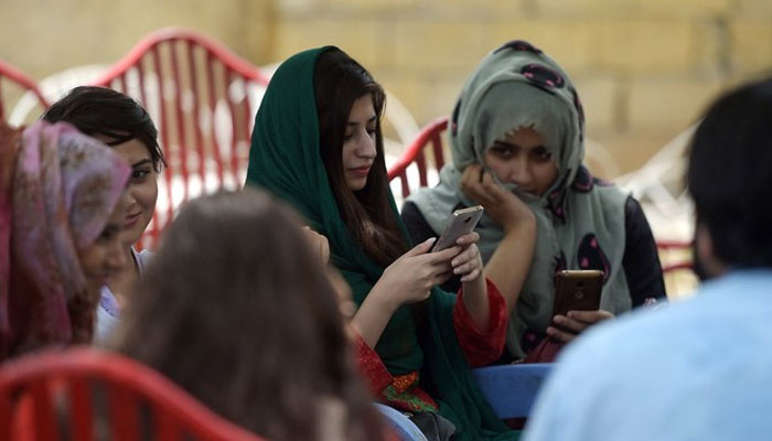 In this picture taken on July 12, 2018, students use their mobile phones at a campus in Islamabad.
