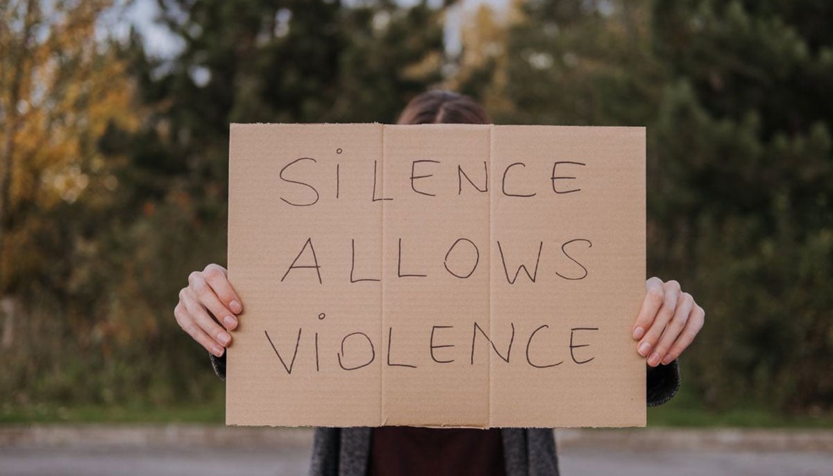 A representational image of a woman holding a placard on DV and IPV awareness. — Canva