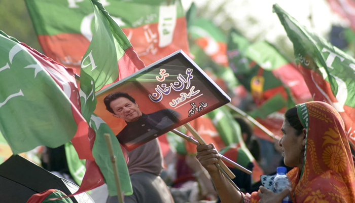 Supporters of PTI hold party flags during a public gathering (jalsa) at Parade Ground, in Islamabad. — Online