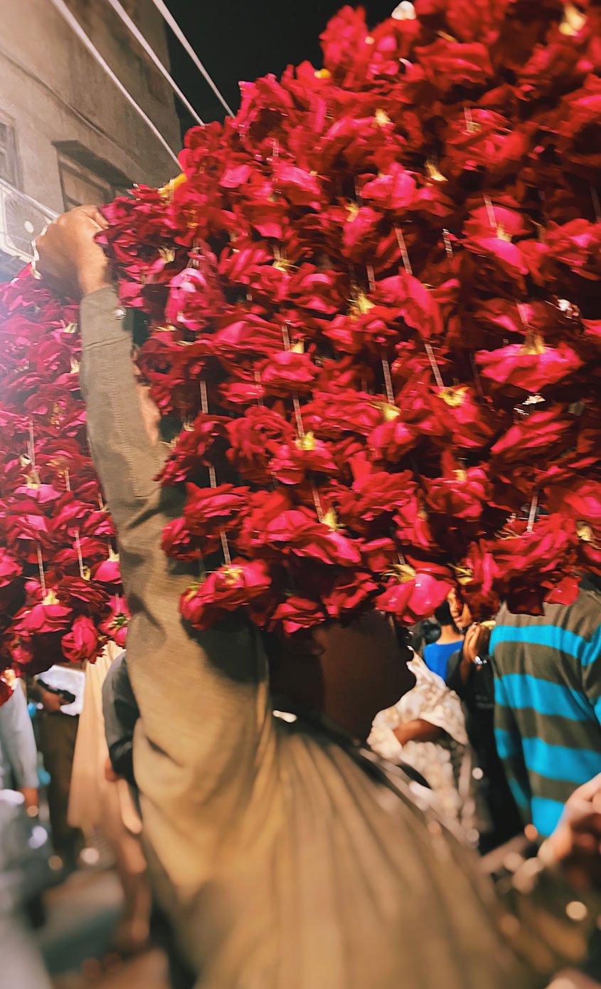 Man sells flowers on the street outside Bibi Pak Daman Mazar. — Photo by author
