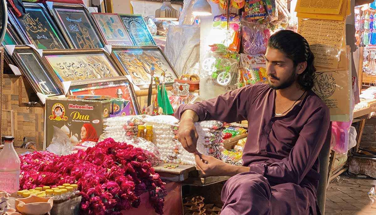 A young man sits outside his stall selling devotional paraphernalia outside Bibi Pak Daman Mazar. — Photo by author