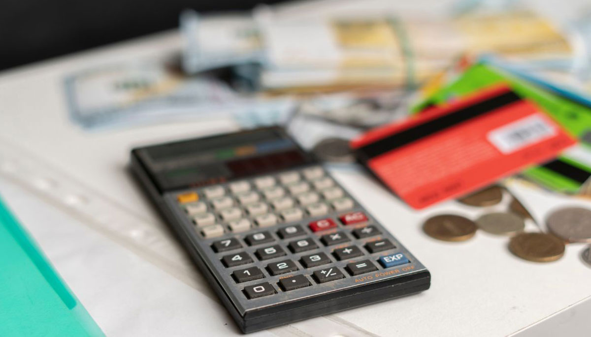 A representational image of a calculator, coins, cards and bank notes. — Canva