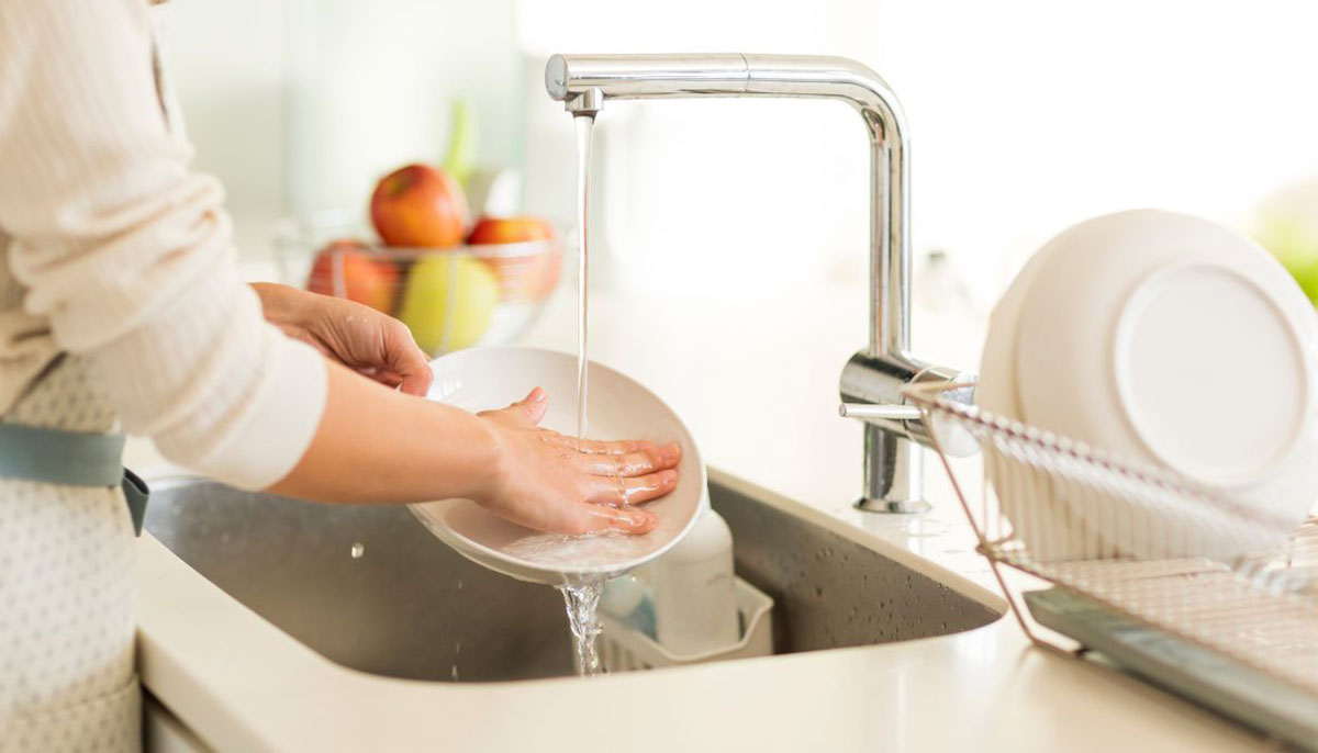 A representational image of a woman washing the dishes. — Canva