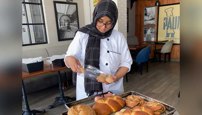 Rida arranging a variety of buns on a baking tray at Paul Bakery & Café - Photo by Rida