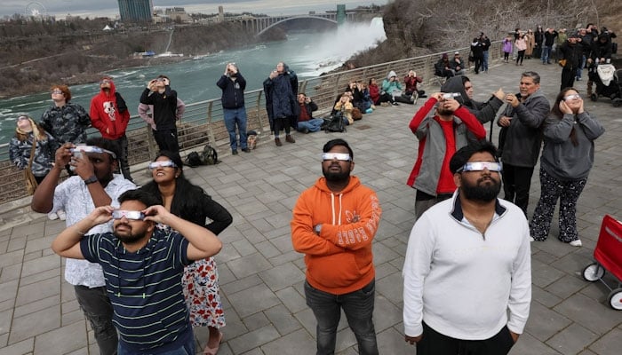 People look to the sky as the moon partially eclipses the sun at Niagara Falls, New York, U.S. April 8, 2024. REUTERS